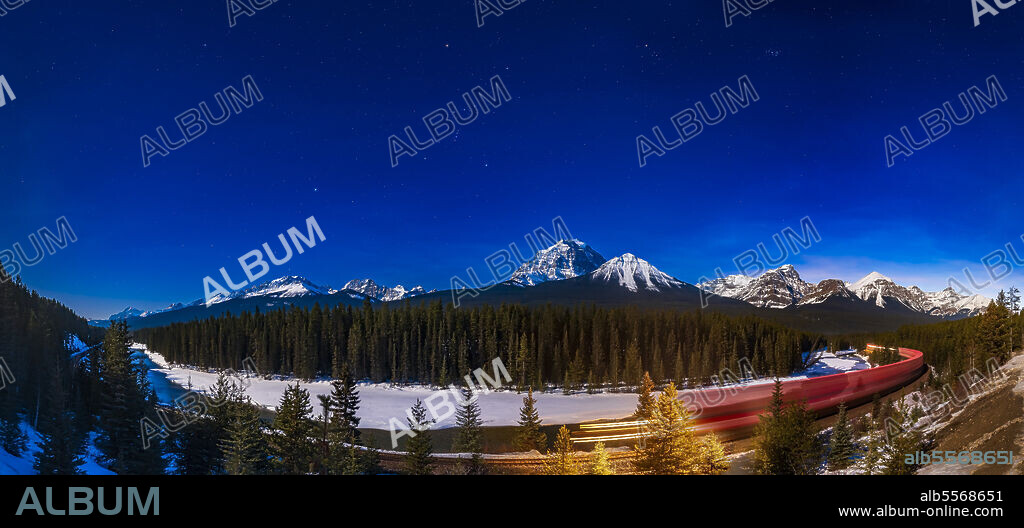 March 19, 2019 - A panorama of Morants Curve, a famous viewpoint on the Bow River in Banff National Park, Canada, with an eastbound train on the CPR tracks under the stars of the winter sky. Illumination is from the 13-day gibbous moon off frame at left. Orion is at centre; Sirius and Canis Major at left; and Taurus and the Pleiades at right. The main peak at centre is Mount Temple; the peaks at right are the ones around Lake Louise.