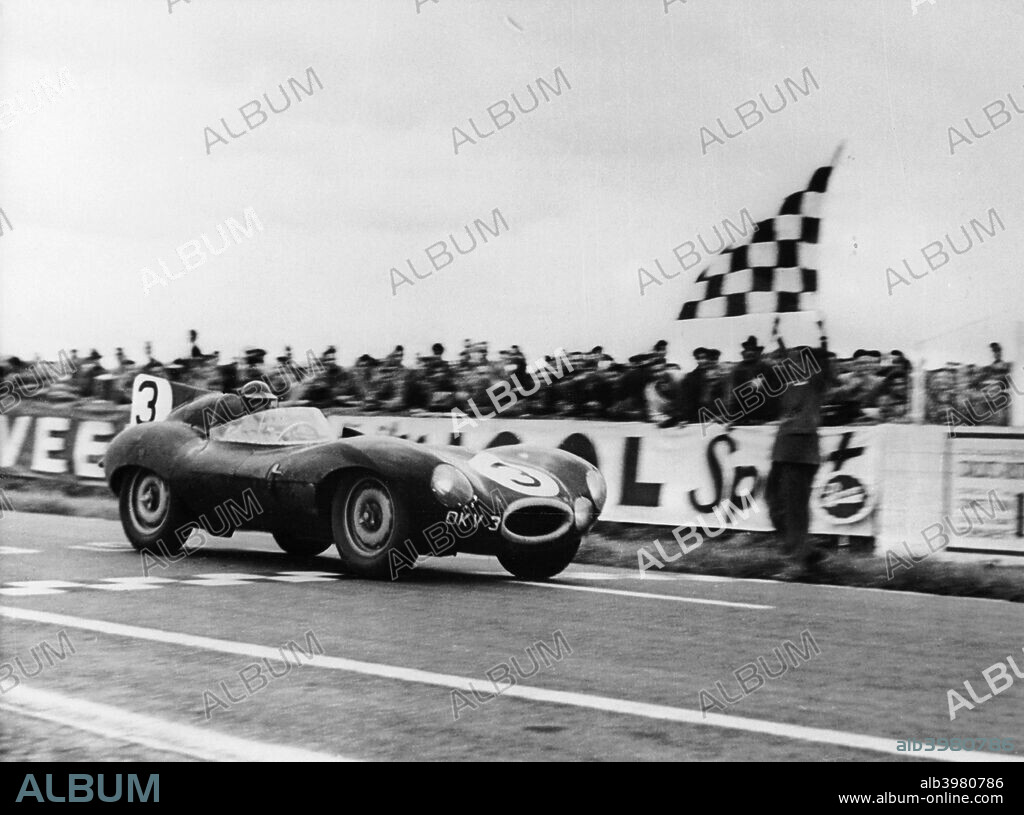 Ken Wharton in a Jaguar D Type passing the chequered flag during the Rheims 12 Hours Race, France, 3rd July 1954. Wharton shared the car with Peter Whitehead and they went on to win the race. Wharton was killed driving a Ferrari Monza sports car in New Zealand 3 years later.