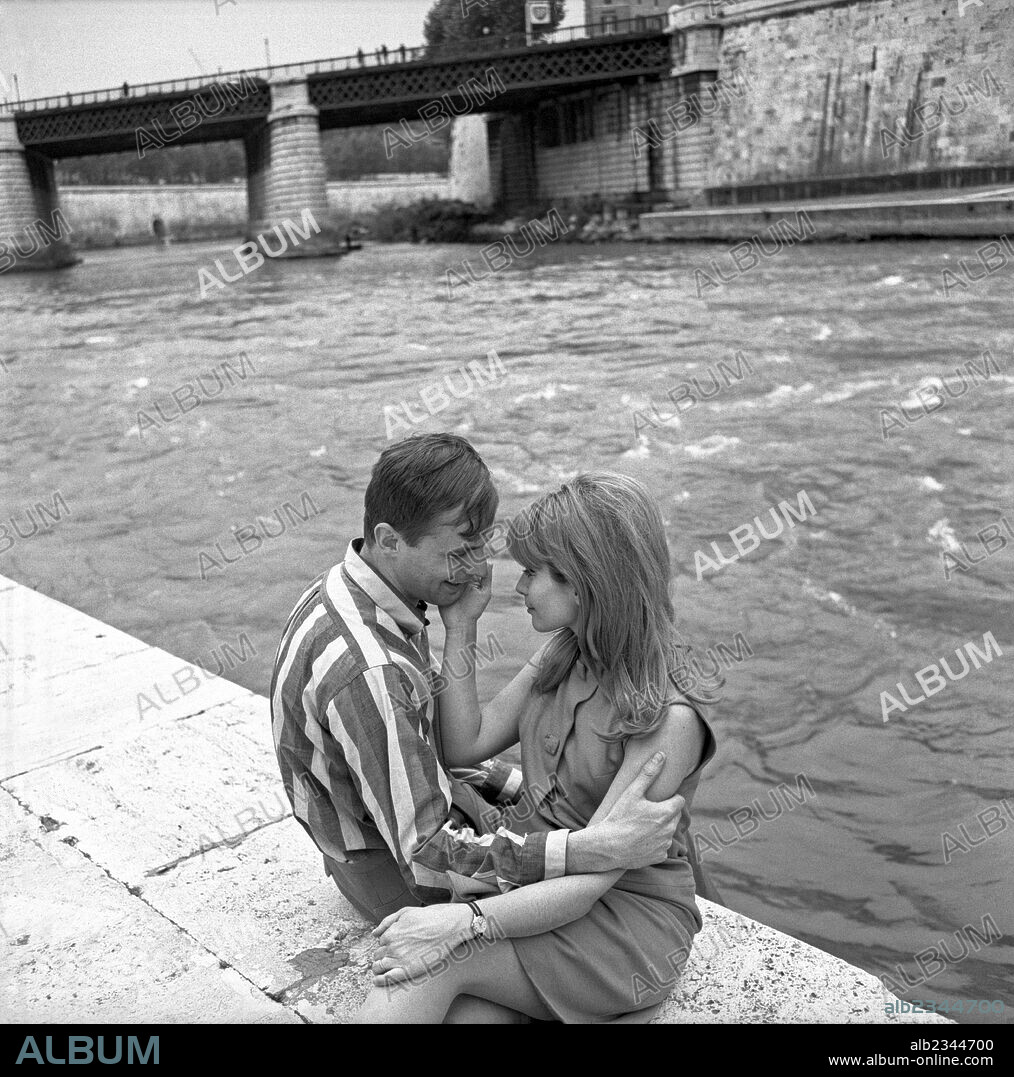 Two loving engaged people hugging each other. Two loving engaged people hugging each other seated by the river. Italy, 1960s.