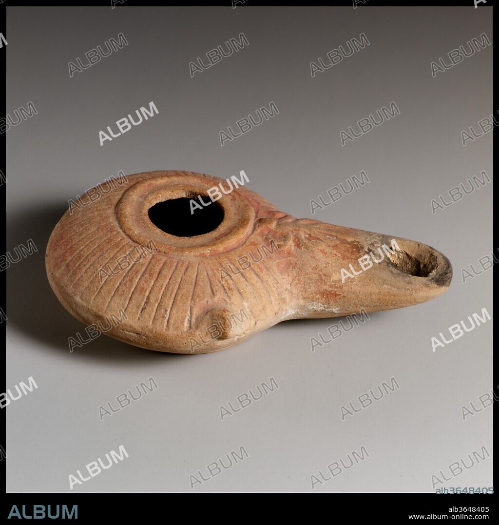 Terracotta oil lamp. Culture: Greek. Dimensions: Overall: 1 x 3 3/8 in. (2.5 x 8.6 cm).
Wheel-made body, with applied long nozzle. Large central filling hole, surrounded by a plain band and an incised circle; convex sloping shoulder decorated with radiating incised lines and with a single projecting knob at edge of left side; palmette in relief along top of nozzle; squat, carinated body. Raised, flat base.
Intact.