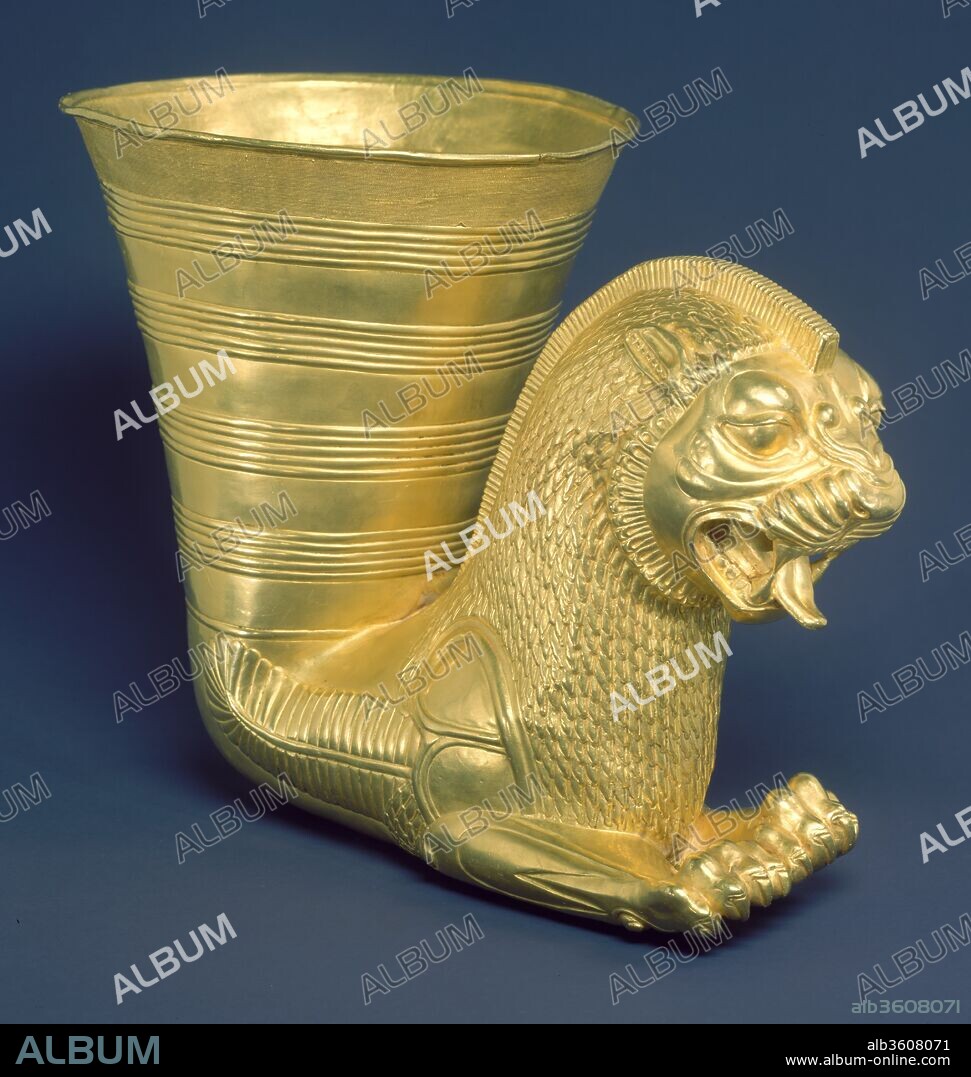 Vessel terminating in the forepart of a fantastic leonine creature. Culture: Achaemenid. Dimensions: H. 17 cm. Date: ca. 5th century B.C..
Horn-shaped vessels ending in an animal's head have a long history in the Near East as well as in Greece and Italy. Early Iranian examples are straight, with the cup and animal head in the same plane. Later, in the Achaemenid period, the head, or animal protome, was often placed at a right angle to the cup, as in this piece. In the manufacture of this gold vessel, several parts were invisibly joined by brazing, which demonstrates superb technical skill. One hundred and thirty-six feet of twisted wire decorate the upper band of the vessel in forty-four even rows, and the roof of the lion's mouth is raised in tiny ribs. Typical of Achaemenid style, the ferocity of the snarling lion has been tempered and restrained by decorative convention. The lion has a crest running down his back; his mane has the disciplined appearance of a woven material; and his flanks are covered by an ostrich plume. The inclusion of the plume, a departure from convention, suggests that this lion is winged and has some supernatural significance.