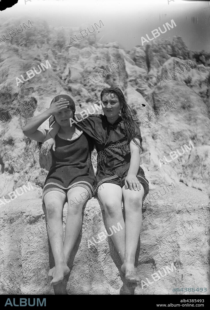 Glass Negative - Girls in Bathing Costumes, circa 1920s - 1930s, Black and white 1/6th plate glass negative of a two young women seated together on a sea wall or bathing pool wall, in their swimming/bathing costumes. collection of products, promotional materials, photographs and working life artefacts, when the Melbourne manufacturing plant at Coburg closed down. manufactured.