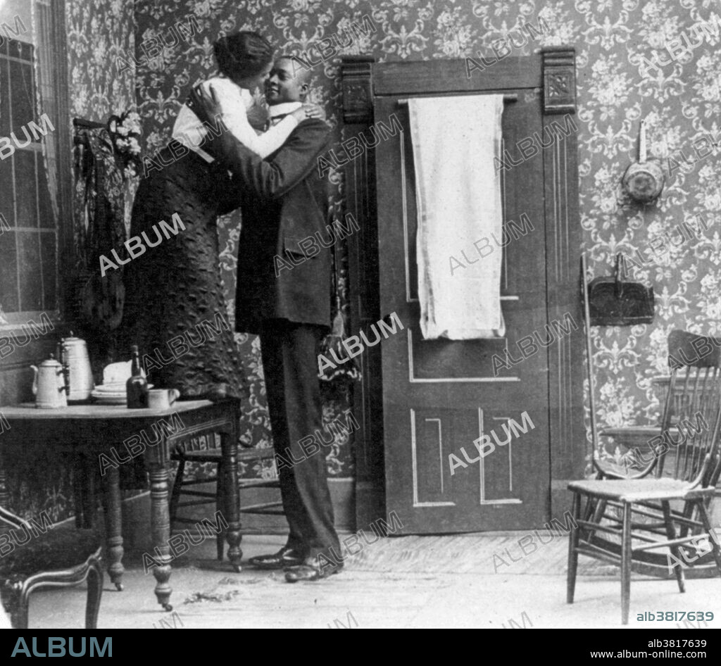 Unidentified African-American woman standing on table and embracing a tall African-American man. Gigantism, also known as giantism, is a condition characterized by excessive growth and height significantly above average. In humans, this condition is caused by over-production of growth hormone in childhood resulting in people between 7 feet and 9 feet in height.