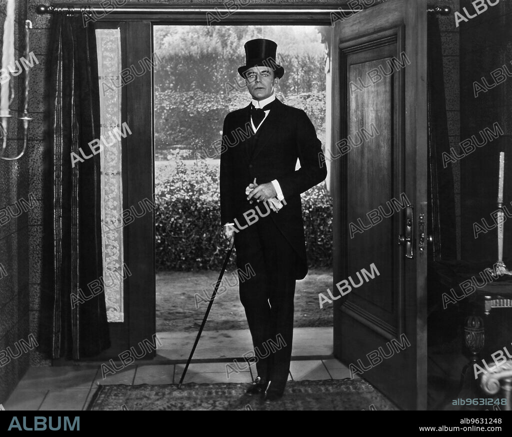 Hollywood, California, c 1918 Silent film star and actor House Peters enters a house wearing a tuxedo, a top hat, and carrying a cane.