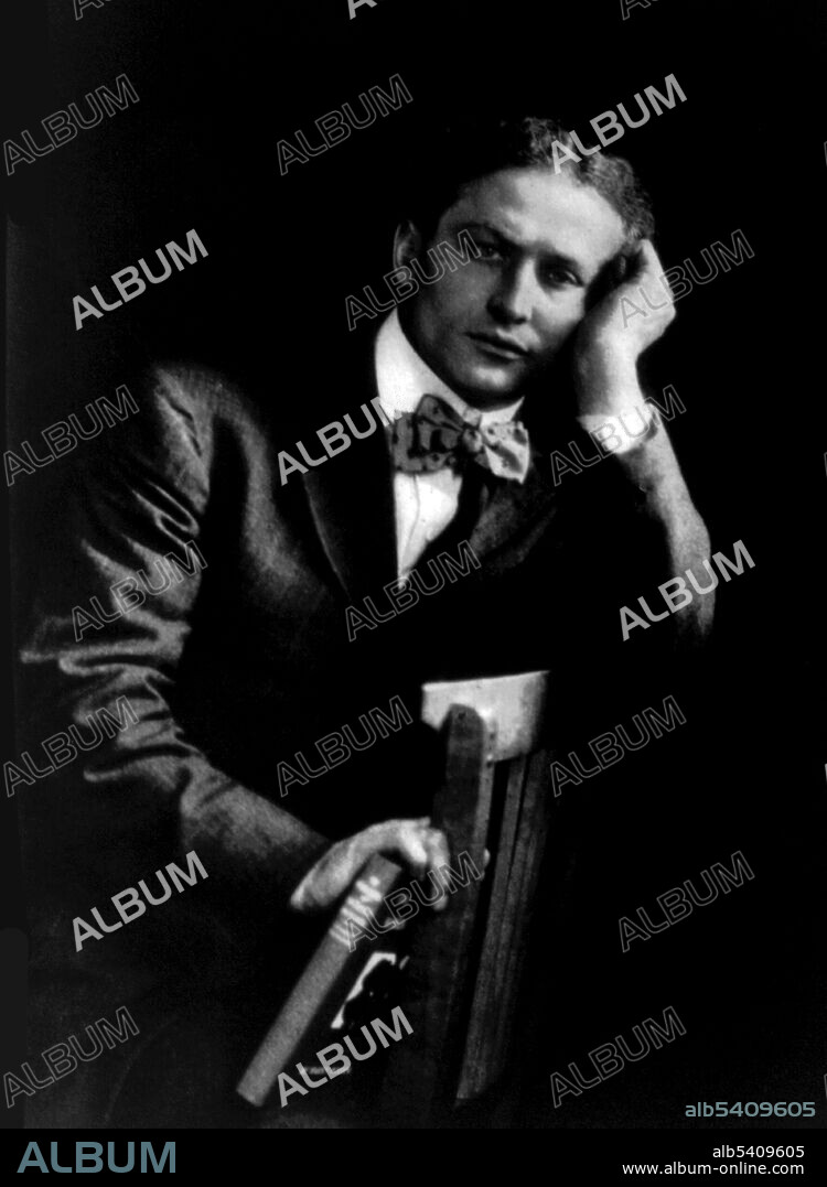 Houdini holding "The Unmasking of Robert-Houdin". Harry Houdini (1874 - 1926) was a Hungarian-American illusionist and stunt performer, noted for his sensational escape acts. His repertoire included chains, ropes slung from skyscrapers, straitjackets under water, holding his breath inside a sealed milk can, and being buried alive. No photographer credited, 1908 (cropped and cleaned).