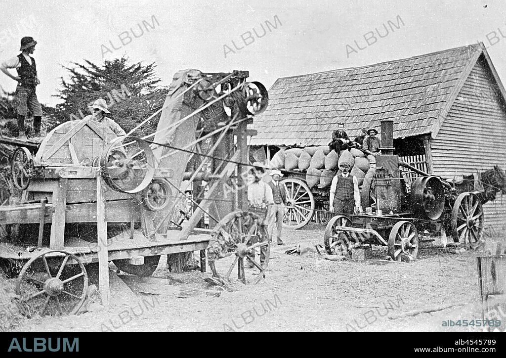 Negative - Hornsby Oil Engine & Chaff Cutter, 'Amphitheatre' Station, Victoria, 1908, A chaff cutting machine at 'Amphitheatre' station. It was powered by a Hornsby oil engine. To the right of the image is a building which is surrounded by a fence, it is made of Victorian timber and has a slate roof. In front of the building three men sit on a cart which is loaded with sacks, and has two horses attached. The men in the image are wearing hats, vests, boots and some are wearing.