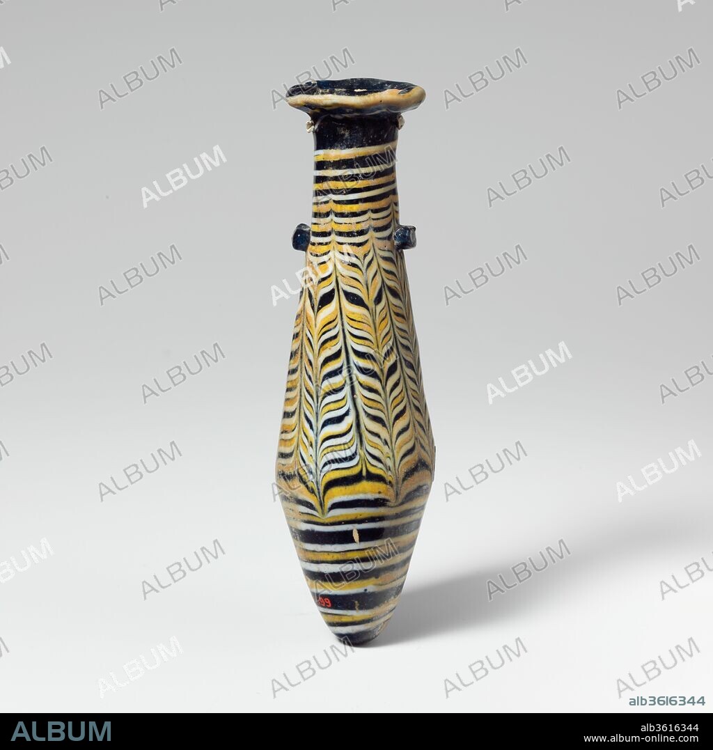 Glass alabastron (perfume bottle). Culture: Greek, Eastern Mediterranean. Dimensions: H.: 5 1/16 in. (12.9 cm)
Diam.: 1 7/16 x 1 1/4 in. (3.6 x 3.1 cm). Date: 2nd-1st century B.C..
Translucent blue, with handles in same color; trails in opaque yellow and opaque white.
Broad rim-disk, uneven and sloping inward with radiating tooling marks on upper and lower surfaces, and jagged, projecting inner lip to neck; cylindrical neck; straight-sided fusiform body expanding downward, then tapering in to pointed bottom; two elongated horizontal lug handles applied at top of body over trails; marvered blob of blue applied over trails on one side at point of greatest diameter.
Trails attached near bottom, drawn up in a spiral to point of carination, tooled into a close-set feather  pattern around side, arranged in seven panels of alternating upward and downward strokes, some slanting and extending onto neck, forming a partial festoon pattern, wound round again in spiral to top of body and on to edge of rim, with white sometimes overlapping yellow.
Intact; some bubbles; very slight dulling, pitting, and iridescent weathering.