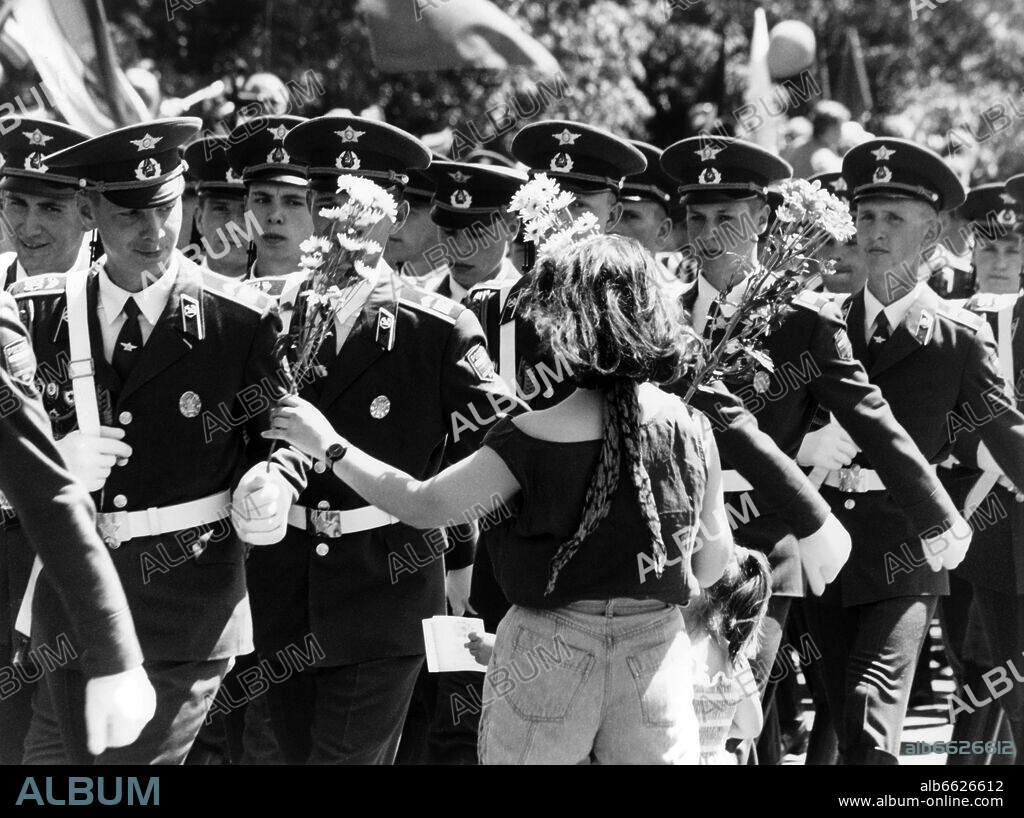 A woman gives flowers to Russian soldiers marching by during a military parade of the Russian army on the occasion of the troop withdrawal from Berlin on the 25th of June in 1994. The Russian Berlin brigade said goodbye with a parade of 1,500 soldiers and a few combat tanks in front of 40,000 spectators. 25/06/1994