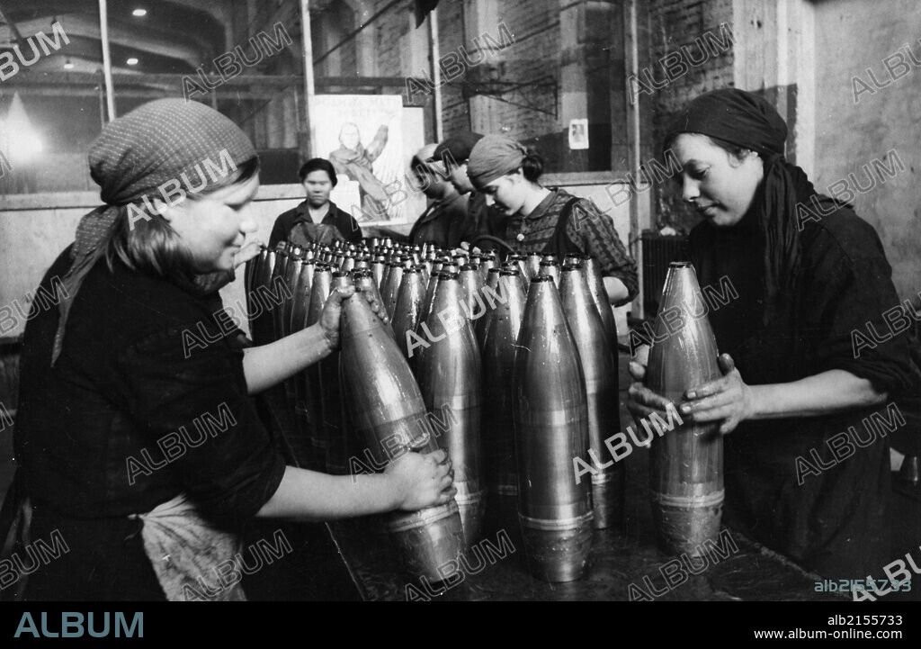 A team of civilian women packers putting grease onto artillery shells at a munitions factory during world war 2.