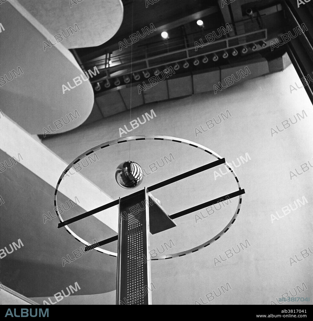 The Foucault Pendulum was installed at the United Nations Headquarters in New York City, NY in 1955. The gold-plated structure weighs 200 lbs. It is suspended 75 feet above the floor of the lobby, over a raised metal ring, some six feet in diameter, and containing an electromagnet in the center. The Foucault Pendulum was a gift to the U.N. form the Netherlands. It provides visual proof of the rotation of the earth. The sphere, 12 inches in diameter, is held by a stainless steel wire which allows the weighted ball to swing freely in any plane. It swings directly over the raised metal ring, its plane shifting slowly in a clockwise direction. A complete cycle will take approximately 36 hours and 45 minutes. The pendulum utilizes the principle first demonstrated by the noted French physicist, Jean Bernard Leon Foucault, in Paris in 1851, when he suspended a heavy sphere from the dome of the Pantheon by a 220 foot wire.