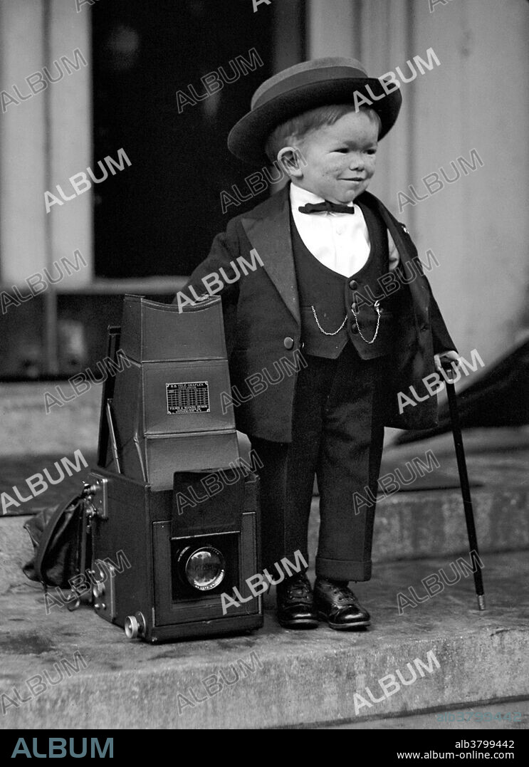 Clarence Chesterfield Howerton (February 9, 1913 - November 18, 1975), AKA Major Mite, was an American circus performer. His career began at a young age, when his father entered him into a local vaudeville show. In 1923, he joined the Ringling Brothers and Barnum & Bailey Circus, where he starred as a major attraction. He was 2 feet 4 inches tall and billed as the smallest man in the world. His small physique was often contrasted alongside larger circus sideshow acts, such as the juvenile obese and the excessively tall. In 1922, he received national press coverage when he visited President Harding at the White House. During the 1930s, he was used as a mascot for the recruitment side of the US Marine Corps. His biggest role in acting was with 1939's The Wizard of Oz, in which he played the part of a trumpet-playing Munchkin, who announced the arrival of the mayor. In contrast to his public persona, Howerton reportedly enjoyed cigars and beer, "often yelled obscenities" and was known to "run the length of a bar, kicking anything in his way". He retired from the entertainment industry in 1949. In 1975, at the age of 62, Howerton died of pneumonia. No photographer credited, 1922.