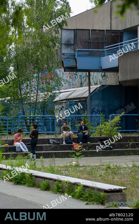 Verlassene Schule. Ehemalige Carl-Diem-Oberschule (Gesamtschule), Am Forstacker 9-11, 13587 Berlin. Anfang der 70er Jahre in Berlin als sog. Mittelstufenzentrum erbaut, 1989 wegen Belastung mit asbesthaltigen Baustoffen geschlossen. Schüler sitzen aud dem Gelände davor. Außenfassade, Teilansicht, Fotografie.