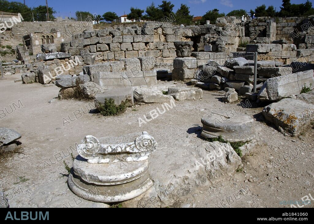 Greece. Ancient Corinth (polis). Ruins of the archaeological site. In the foreground remains of Ionic capital with volutes. Peloponnese region.