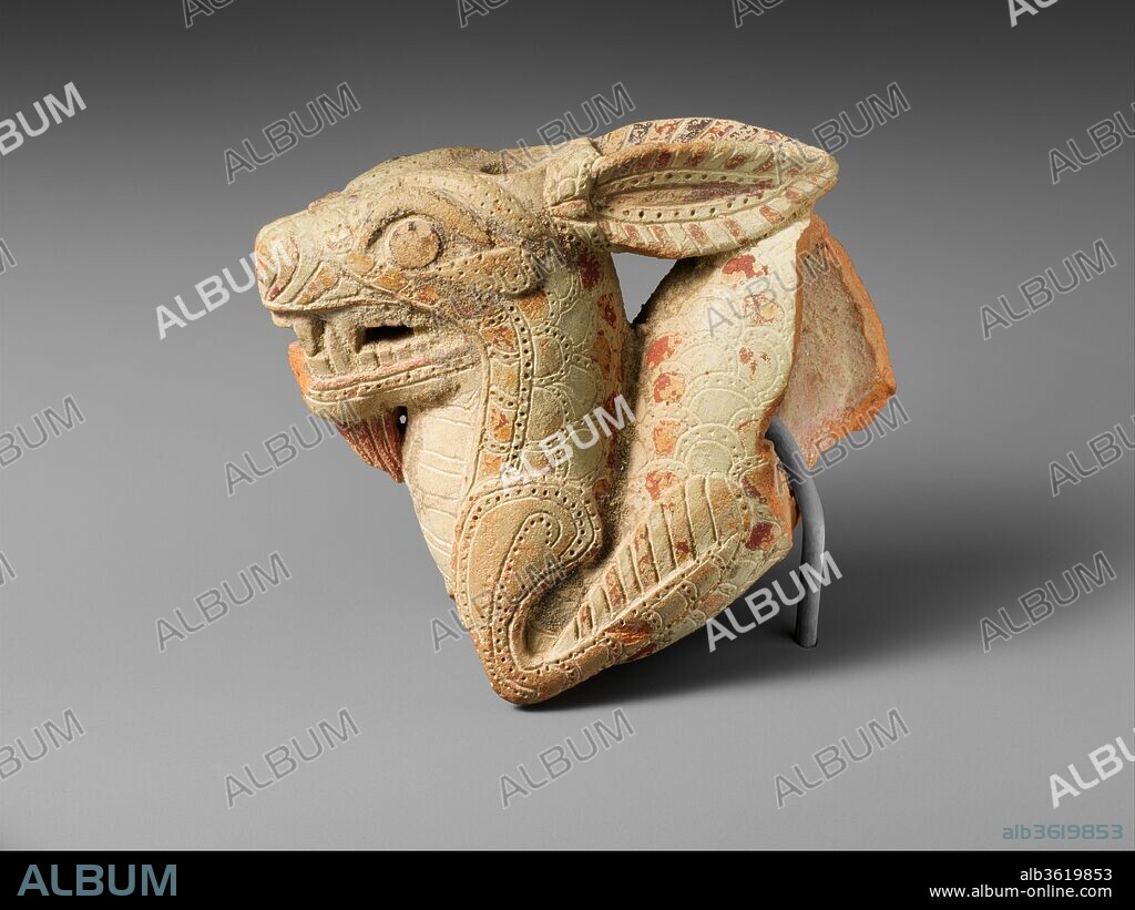 Terracotta vase in the form of a ketos (sea monster). Culture: Greek, Cretan or South Italian. Dimensions: Overall: 3 1/16 x 3 15/16 in. (7.7 x 10 cm). Date: 2nd half of the 7th century B.C..
This spirited sculptural vase is among the earliest extant representations of a Greek ketos, or sea monster. The creature has a formidable leonine head with big eyes and a goatee, a striped belly, scales, and two flipperlike fins. With its long, furry ears pressed back and its large, prominent teeth bared, it gestures menacingly. A hole in the top of the head would have been used to fill the vase, and liquid would have poured out through the hole in the tongue between the large fangs. Except for the loss of the end of the body and tail, the vase is remarkably well preserved, with much added red paint on the ears, face, and alternating scales.
The iconography of the Greek ketos was established in the Archaic period (ca. 600-480 B.C.) and remained amazingly consistent for centuries, long into Roman Imperial times. It is one of the creatures that after the conquests of Alexander the Great (r. 331-323 B.C.) traveled to the East, where it appeared in Gandharan art and influenced representations of monsters from Afghanistan to India. The ketos has even been suggested as a partial inspiration for the Chinese dragon.